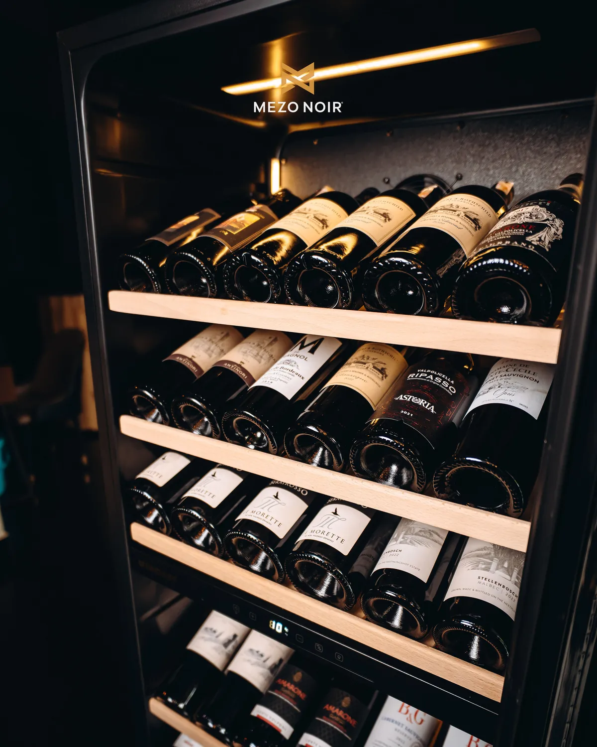 The wine fridge, racked with red and white bottles